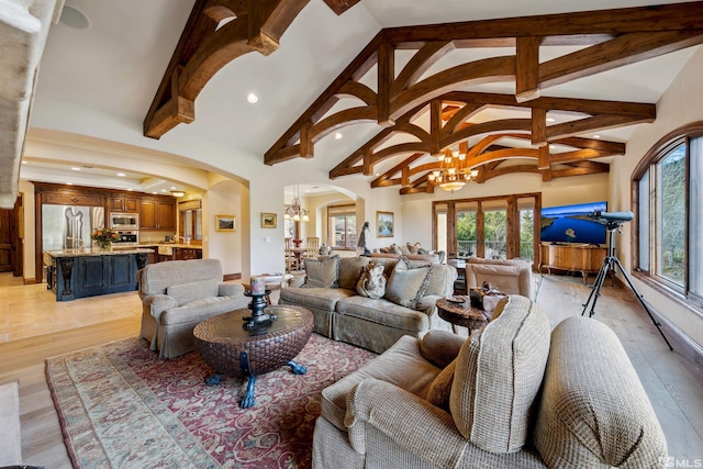 living room with a notable chandelier, light hardwood / wood-style floors, high vaulted ceiling, and beam ceiling