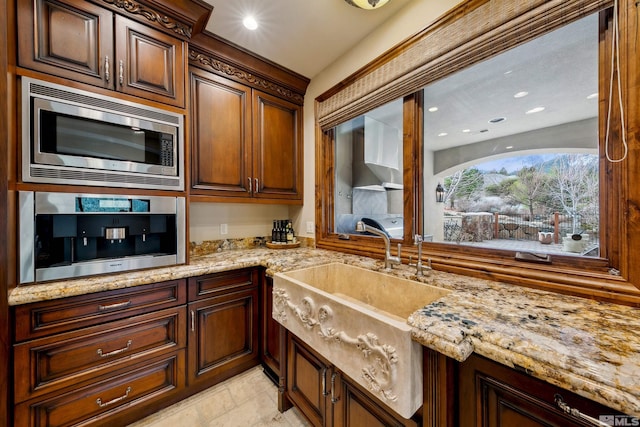 kitchen with sink, stainless steel microwave, and light stone countertops