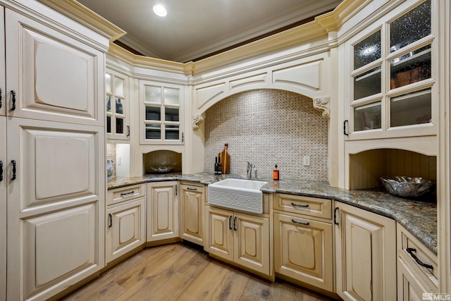 kitchen with light stone counters, light hardwood / wood-style flooring, decorative backsplash, crown molding, and sink