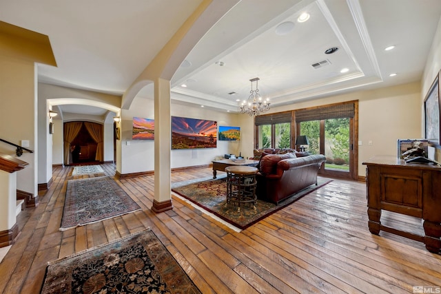 living room featuring a notable chandelier, hardwood / wood-style flooring, and a tray ceiling