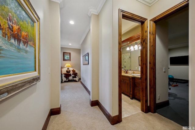 corridor with sink, crown molding, and light colored carpet