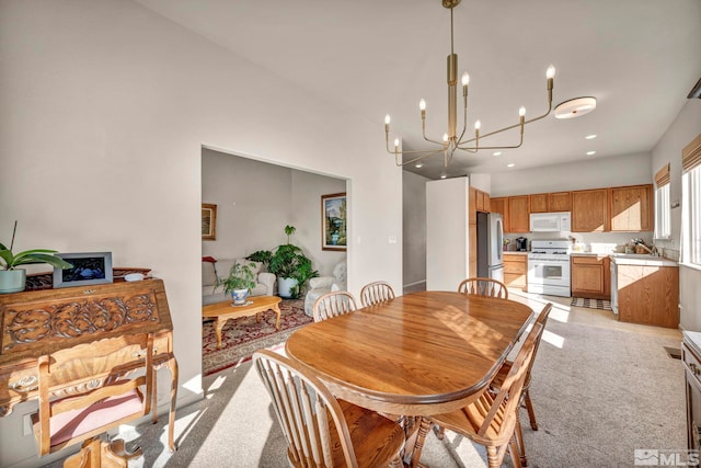 dining area with light carpet and a chandelier