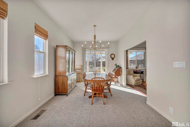 carpeted dining room with a healthy amount of sunlight and a notable chandelier