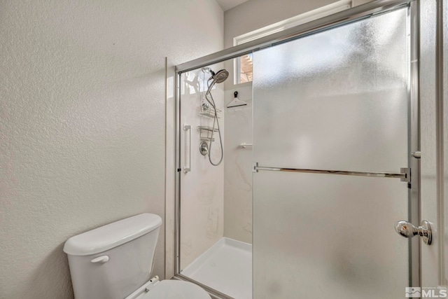 bathroom featuring toilet and a shower with shower door