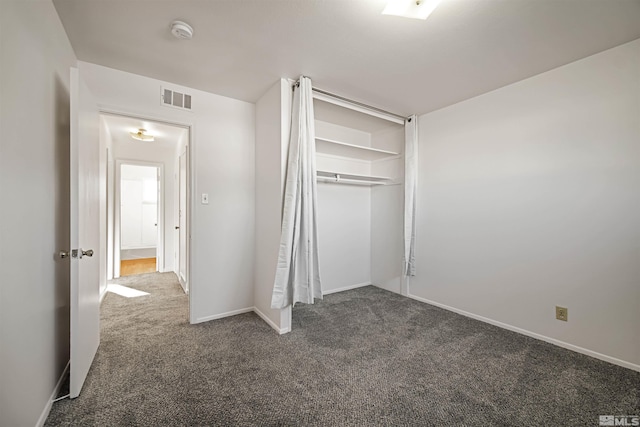 unfurnished bedroom with a closet and dark colored carpet