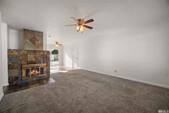 unfurnished living room with ceiling fan, a fireplace, and dark carpet