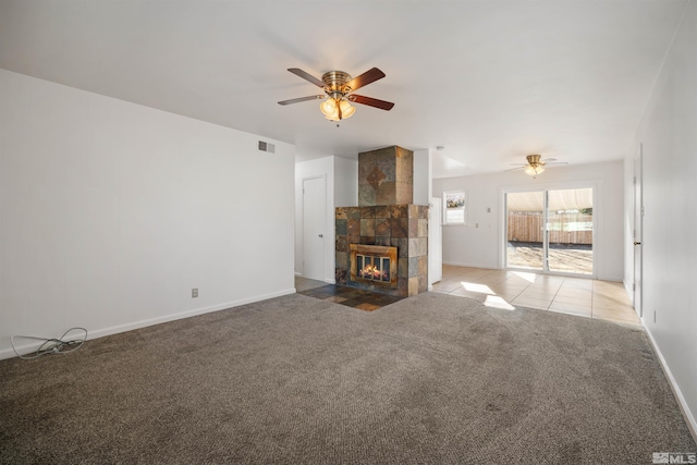 unfurnished living room with a tiled fireplace, light carpet, and ceiling fan