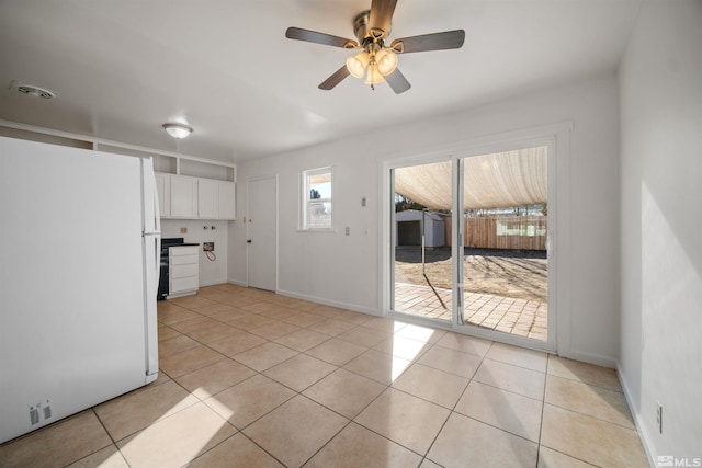 kitchen featuring ceiling fan, white fridge, white cabinetry, and light tile patterned flooring