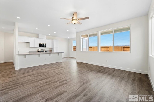 unfurnished living room with dark wood-type flooring and ceiling fan