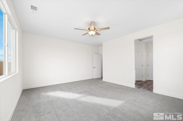 empty room with ceiling fan and dark colored carpet