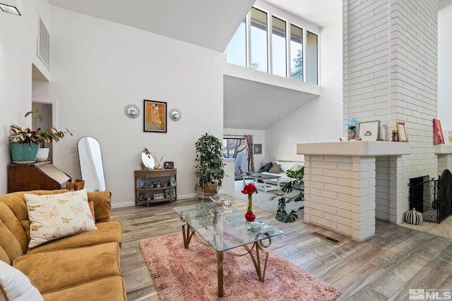 living room with a fireplace, high vaulted ceiling, and light wood-type flooring