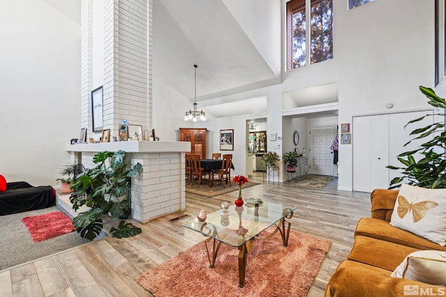 living room featuring light hardwood / wood-style flooring, an inviting chandelier, and high vaulted ceiling