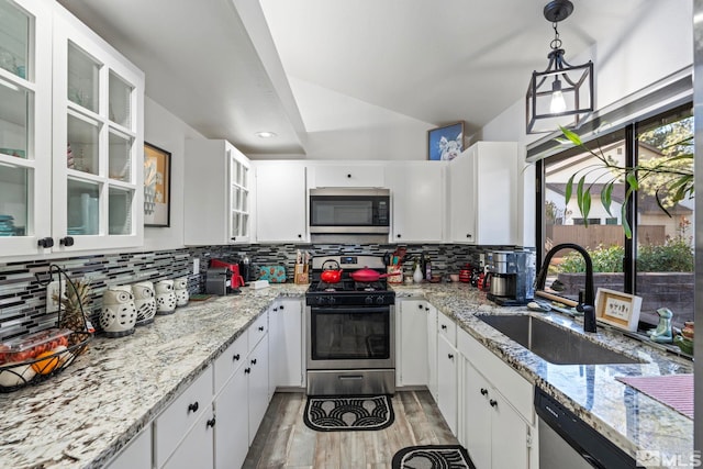 kitchen featuring stainless steel appliances, sink, white cabinetry, light hardwood / wood-style flooring, and pendant lighting