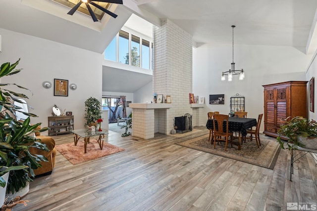 dining room with ceiling fan, light hardwood / wood-style flooring, and high vaulted ceiling