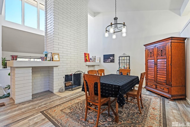 dining room featuring high vaulted ceiling, an inviting chandelier, and light hardwood / wood-style flooring