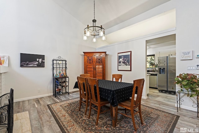 dining space featuring vaulted ceiling, a chandelier, and wood-type flooring