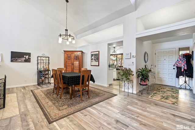 dining room featuring high vaulted ceiling, a chandelier, and light wood-type flooring