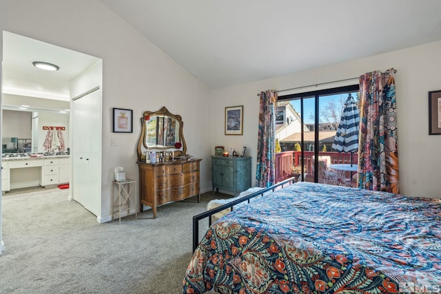 bedroom with ensuite bathroom, vaulted ceiling, and light carpet