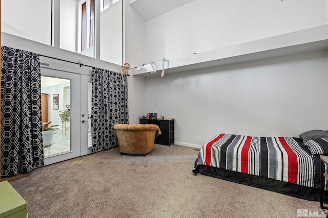 bedroom with a towering ceiling, multiple windows, carpet flooring, and access to outside