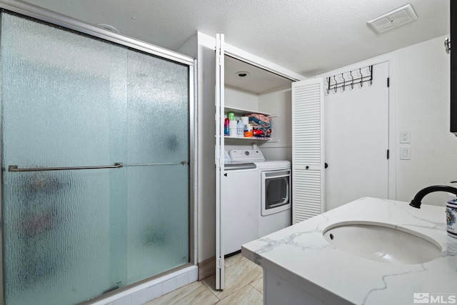 bathroom with independent washer and dryer, a textured ceiling, walk in shower, and vanity