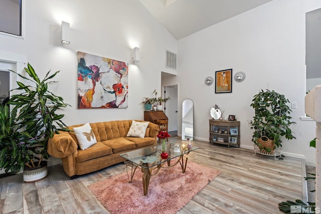 living room with light hardwood / wood-style floors and high vaulted ceiling