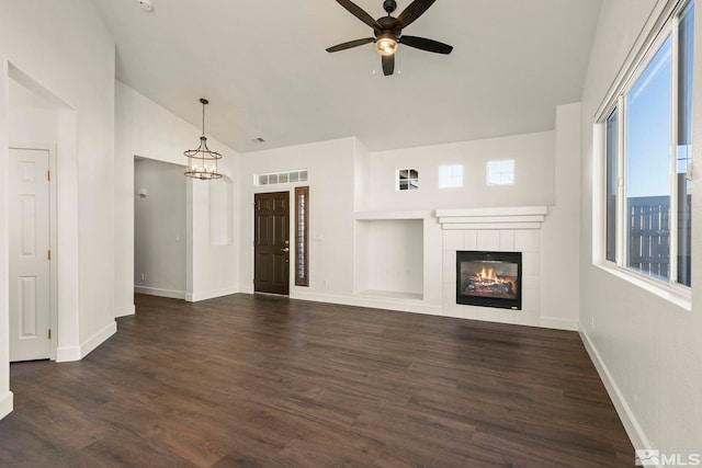 unfurnished living room featuring ceiling fan with notable chandelier, a tile fireplace, lofted ceiling, and dark hardwood / wood-style floors