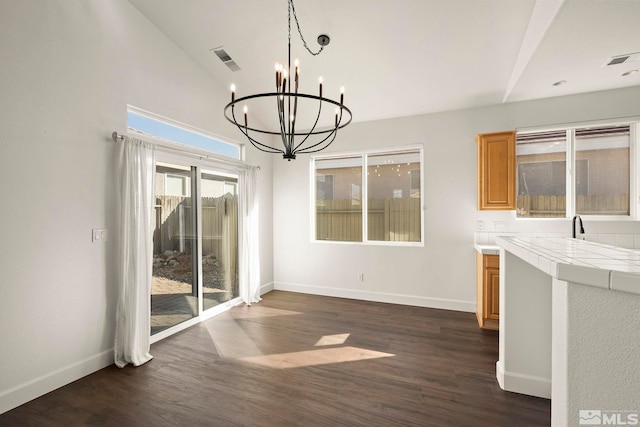 unfurnished dining area with dark hardwood / wood-style flooring, lofted ceiling, and a chandelier