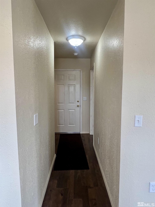 corridor with a textured ceiling and dark hardwood / wood-style floors