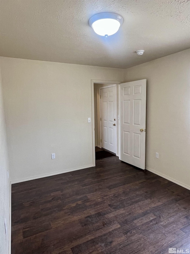 unfurnished room with a textured ceiling and dark wood-type flooring