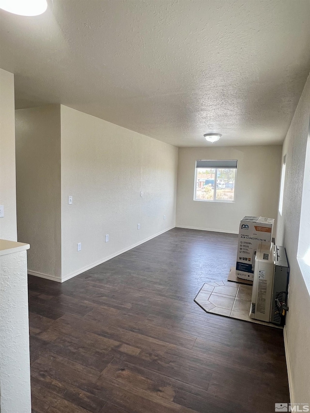 unfurnished living room with dark hardwood / wood-style flooring and a textured ceiling