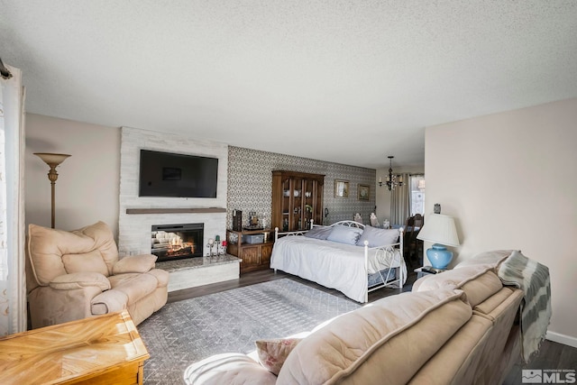 bedroom featuring dark wood-type flooring, a textured ceiling, a multi sided fireplace, and a chandelier