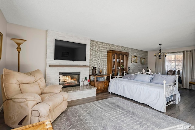 bedroom featuring dark hardwood / wood-style flooring, a fireplace, and an inviting chandelier