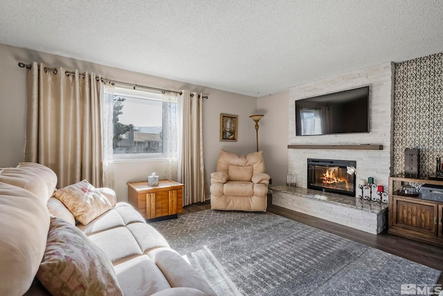 living room with a large fireplace, a textured ceiling, and dark hardwood / wood-style floors