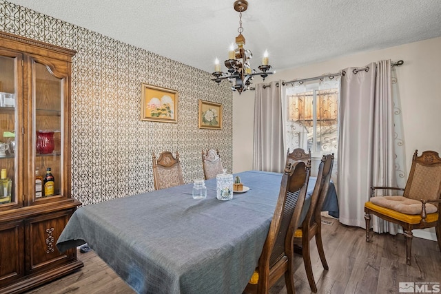 dining area featuring an inviting chandelier, a textured ceiling, and hardwood / wood-style floors