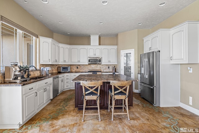 kitchen with a center island, stainless steel appliances, white cabinetry, a breakfast bar area, and sink