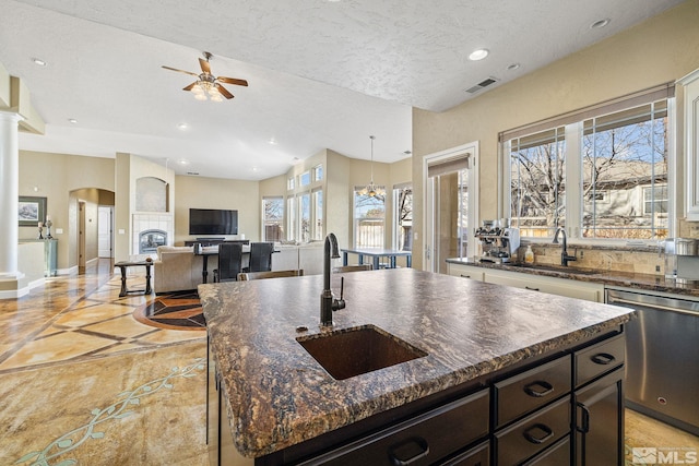 kitchen featuring a kitchen island, dark stone counters, dishwasher, and sink