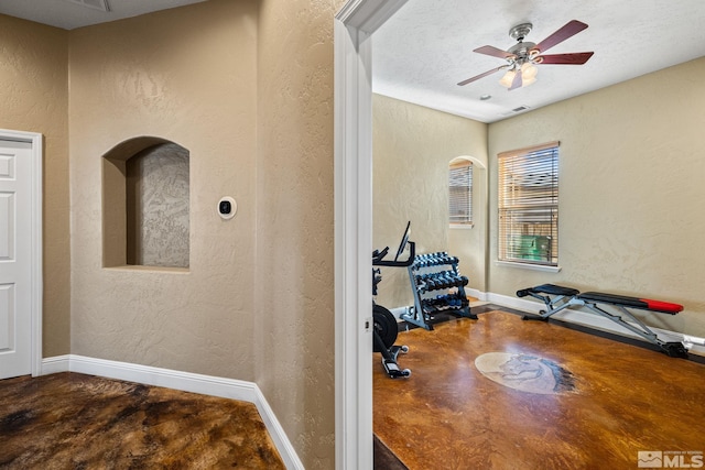 workout room featuring a textured ceiling and ceiling fan