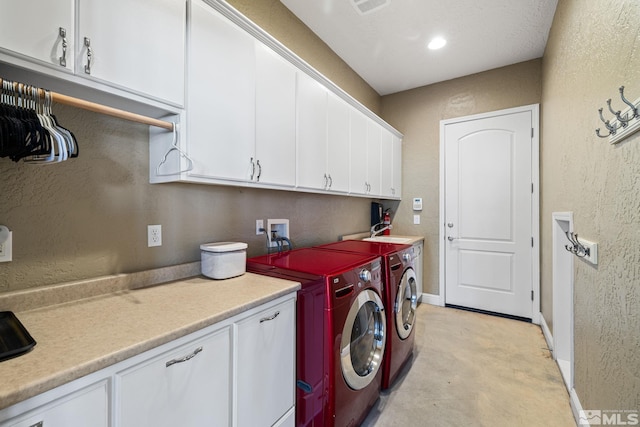 laundry area featuring separate washer and dryer and cabinets