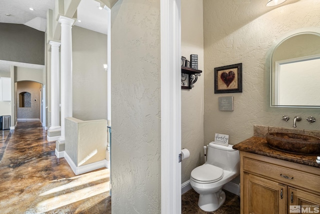 bathroom with toilet, vanity, radiator heating unit, concrete flooring, and decorative columns