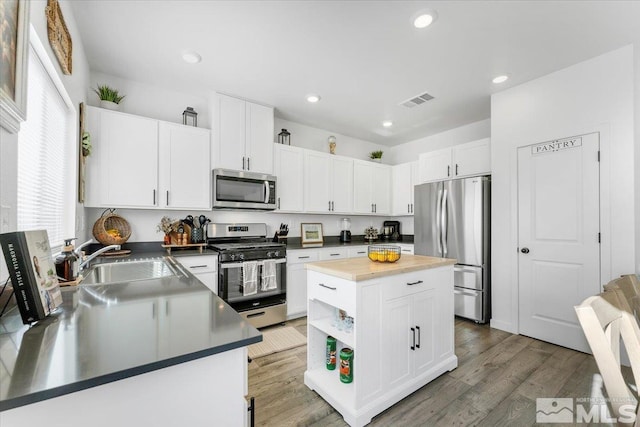 kitchen with sink, a center island, white cabinetry, and appliances with stainless steel finishes