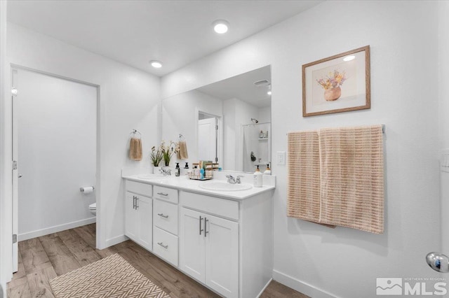 bathroom featuring toilet, a shower, vanity, and hardwood / wood-style floors