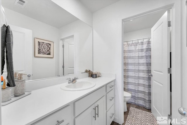 bathroom with toilet, vanity, and hardwood / wood-style floors