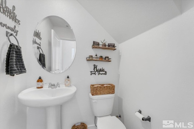 bathroom featuring toilet, a textured ceiling, and vaulted ceiling