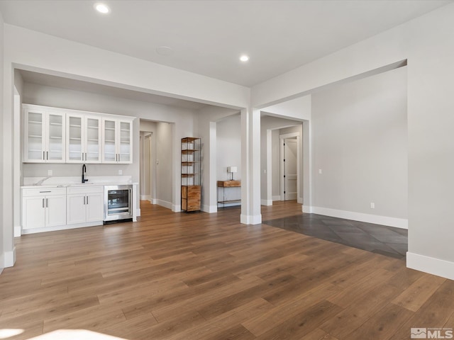 unfurnished living room with beverage cooler, wet bar, and dark hardwood / wood-style floors