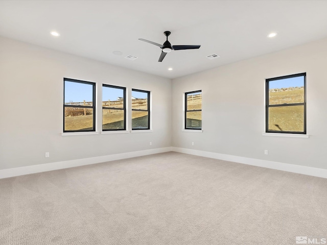 spare room with a wealth of natural light, ceiling fan, and light carpet