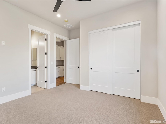 unfurnished bedroom featuring ensuite bathroom, ceiling fan, a closet, and light carpet