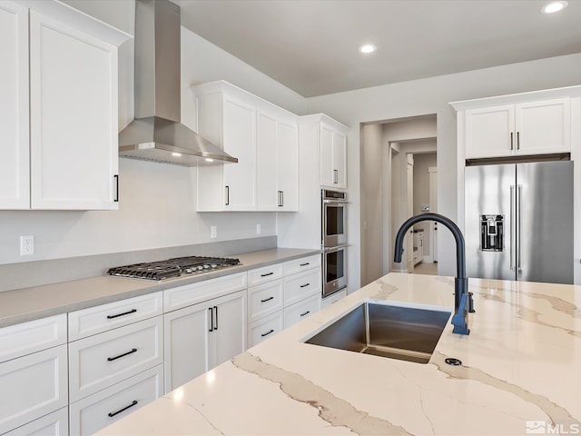 kitchen with sink, white cabinets, wall chimney range hood, and appliances with stainless steel finishes