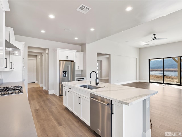 kitchen featuring light stone countertops, appliances with stainless steel finishes, white cabinetry, and sink