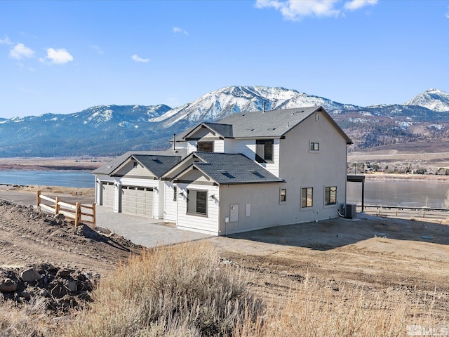 exterior space featuring central AC, a water and mountain view, and a garage