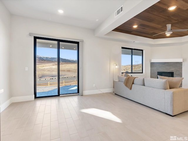 living room featuring ceiling fan, wood ceiling, a tile fireplace, and a mountain view